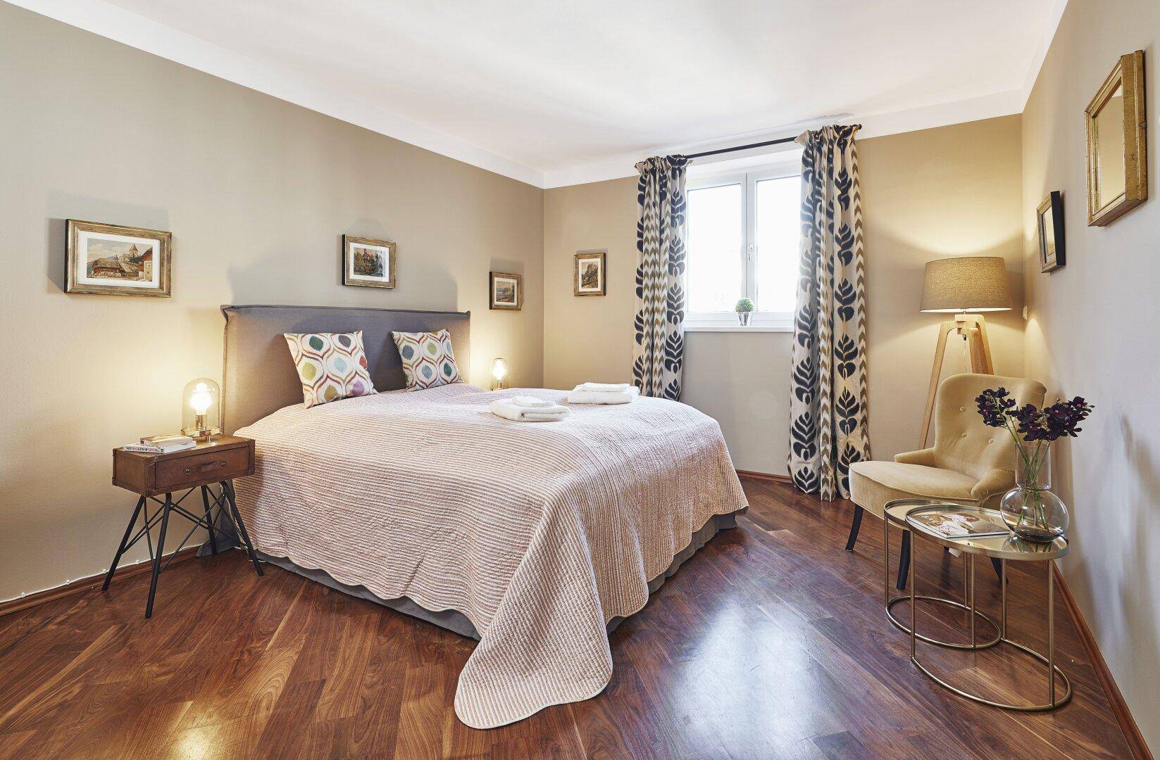 Gemütliches Schlafzimmer mit Holzboden, Doppelbett und stilvoller Einrichtung.