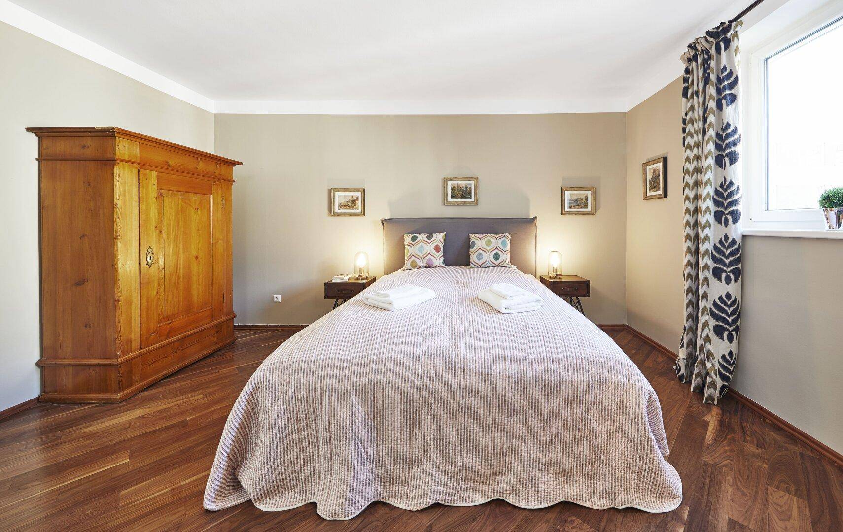 Helles Schlafzimmer mit Holzboden, großem Kleiderschrank und Doppelbett.