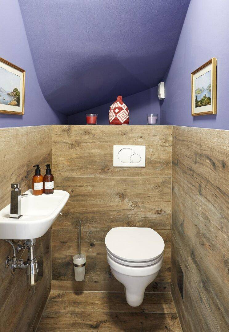 Modernes Gäste-WC mit Holzverkleidung, Wand-WC und kleinem Waschbecken.