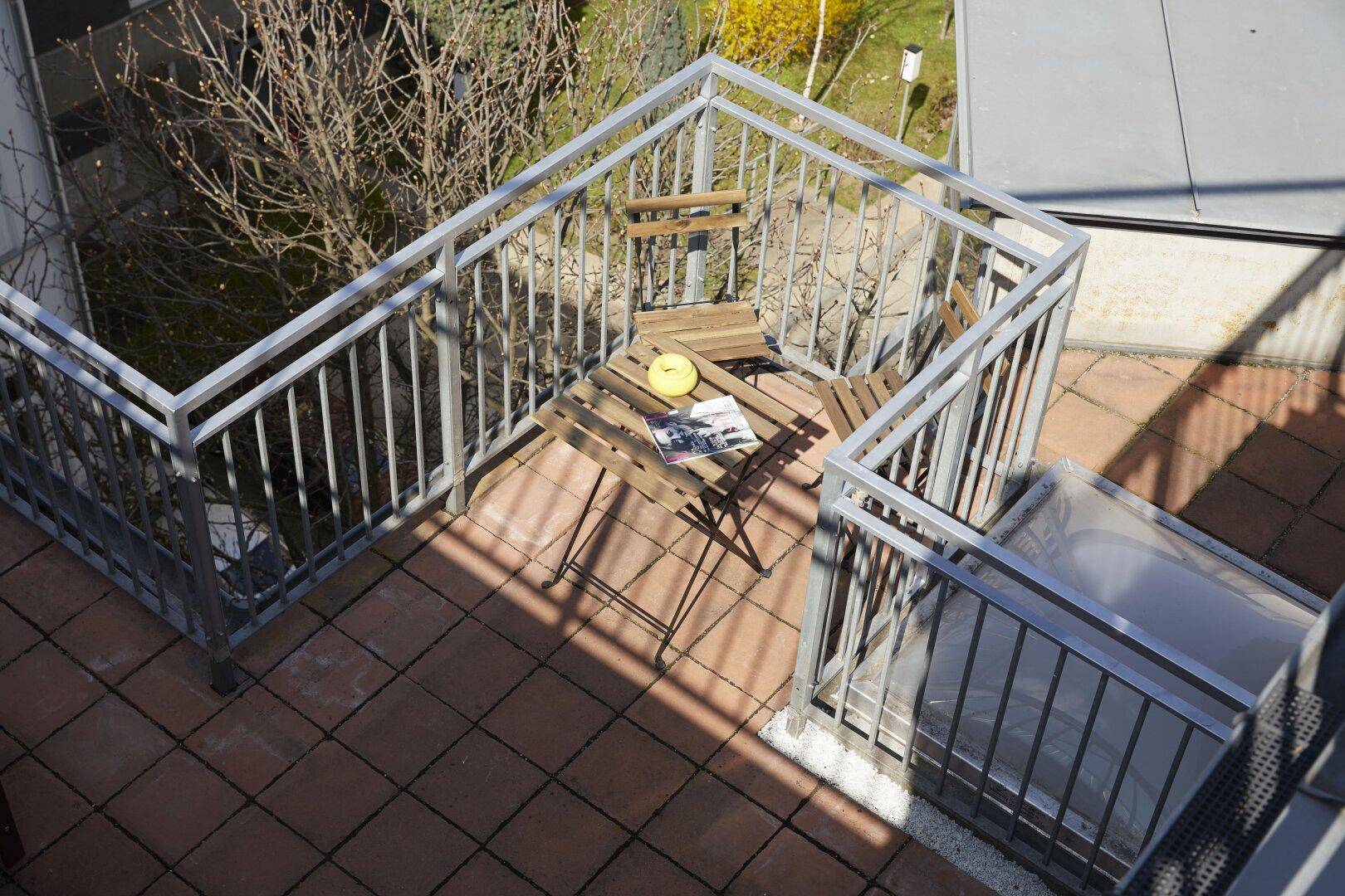 Kleiner Balkon mit Metallgeländer und Sitzgelegenheiten im Freien.