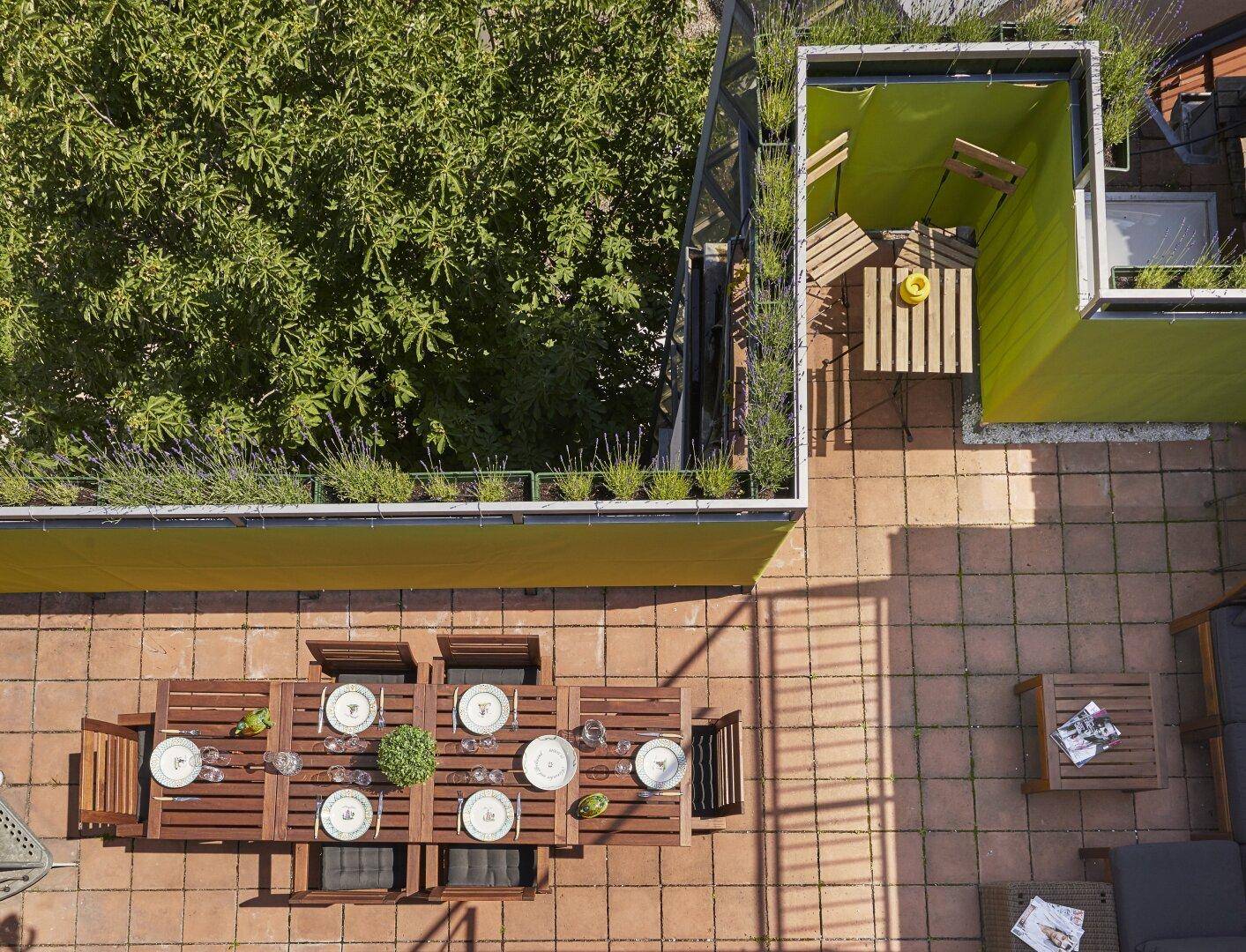Vogelperspektive einer Dachterrasse mit Essbereich, Lounge und grünen Pflanzen.