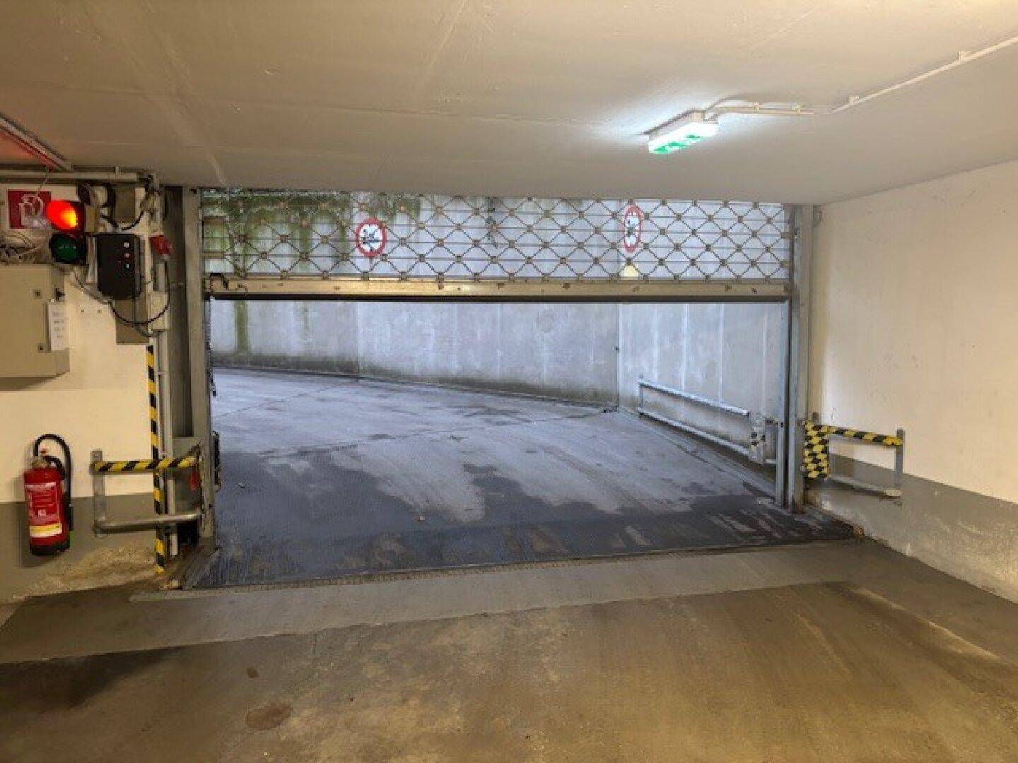 Einfahrt zur Tiefgarage mit Rolltor und Sicherheitsleuchten.