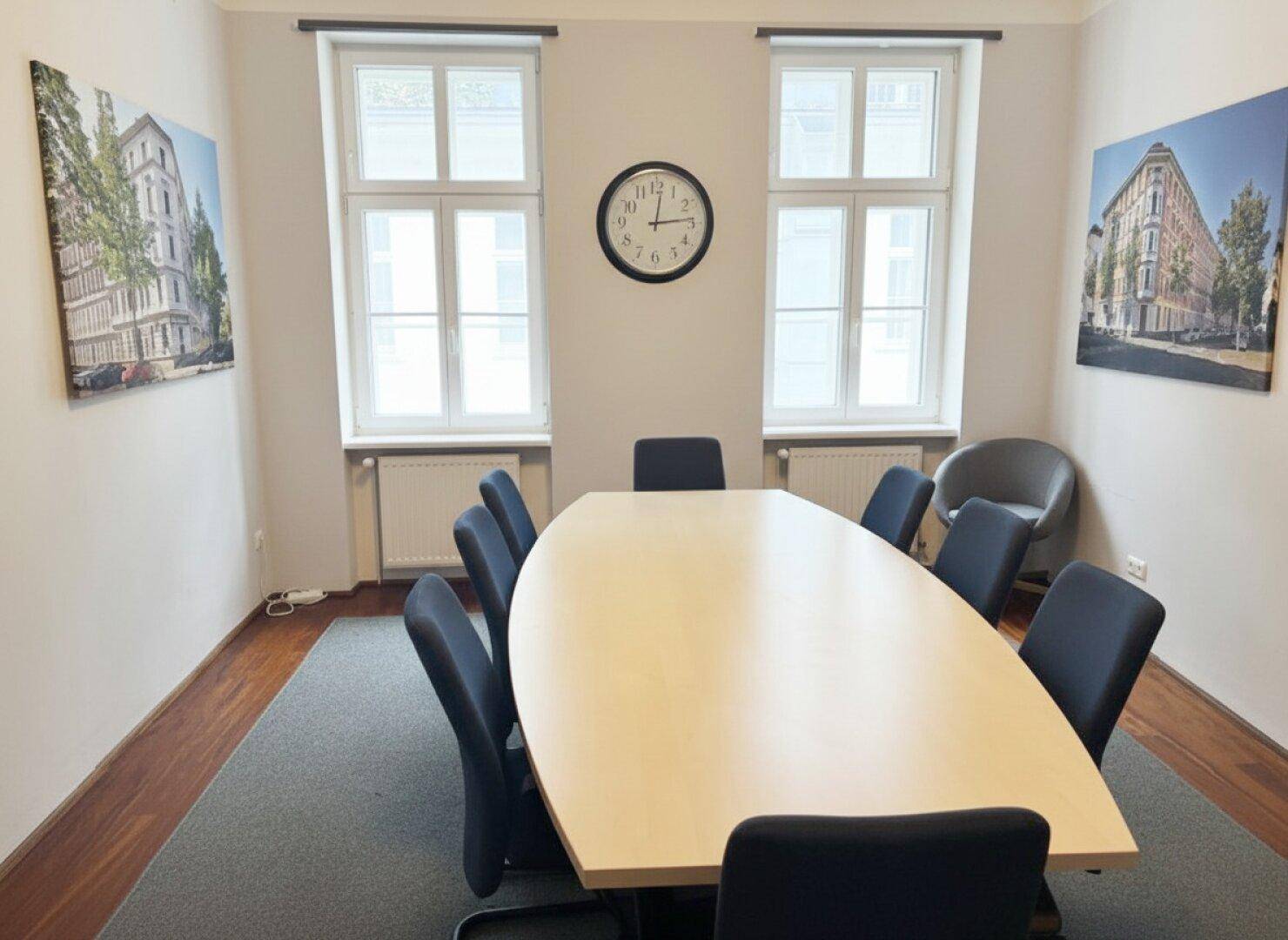 Geräumiger Konferenzraum mit großem ovalen Tisch, Teppichboden und hohen Fenstern.