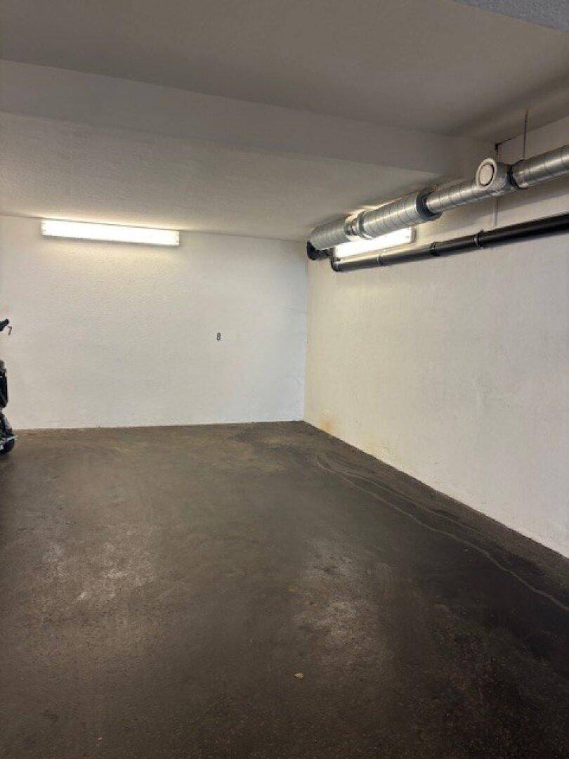 Geräumiger Abstellraum oder Garagenbereich mit weißen Wänden und Betonboden.