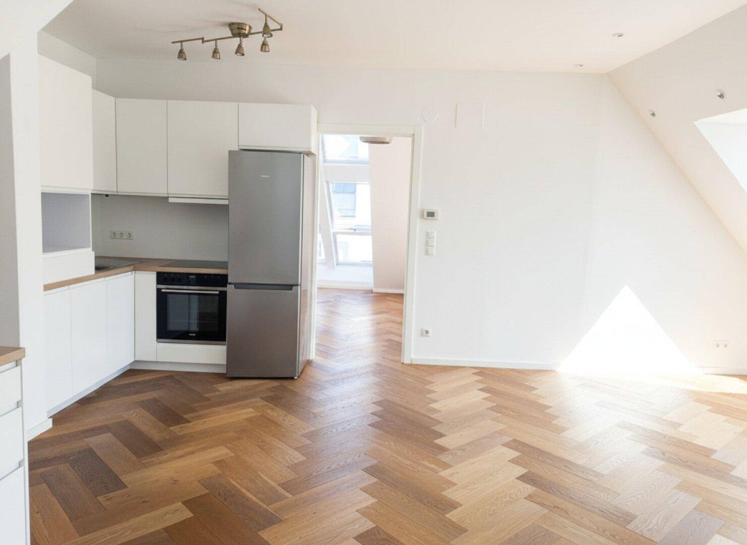 Moderne Küchenzeile mit weißen Schränken, Holz-Arbeitsplatte und integrierten Geräten.