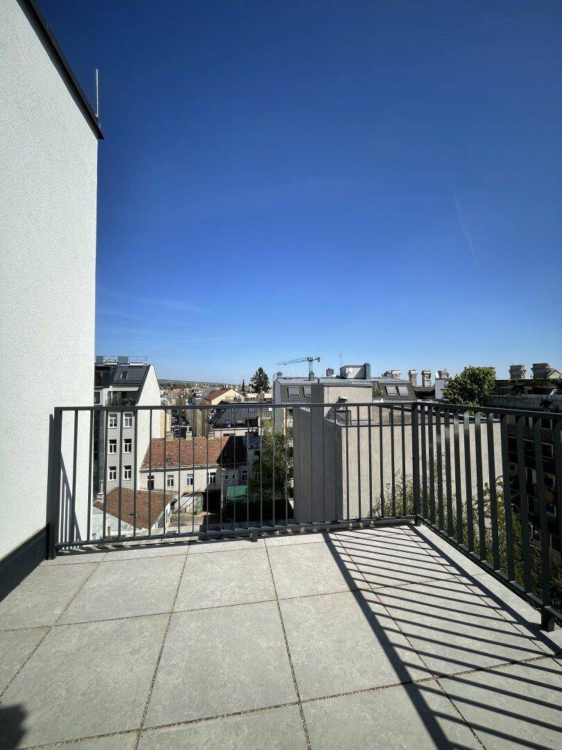 Geräumige Dachterrasse mit Fliesenboden und Metallgeländer, ideal für Entspannung im Freien.