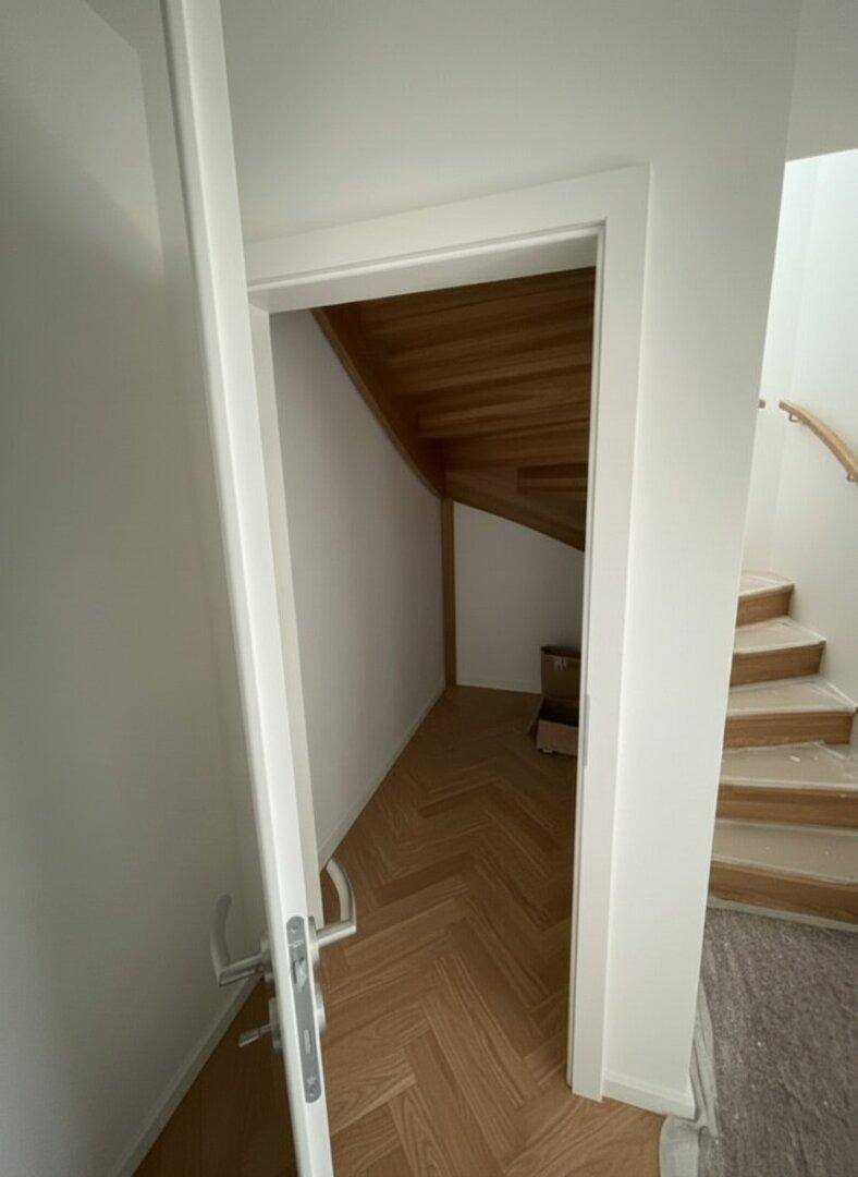 Praktischer Stauraum unter der Treppe mit hellem Fischgrätparkett.