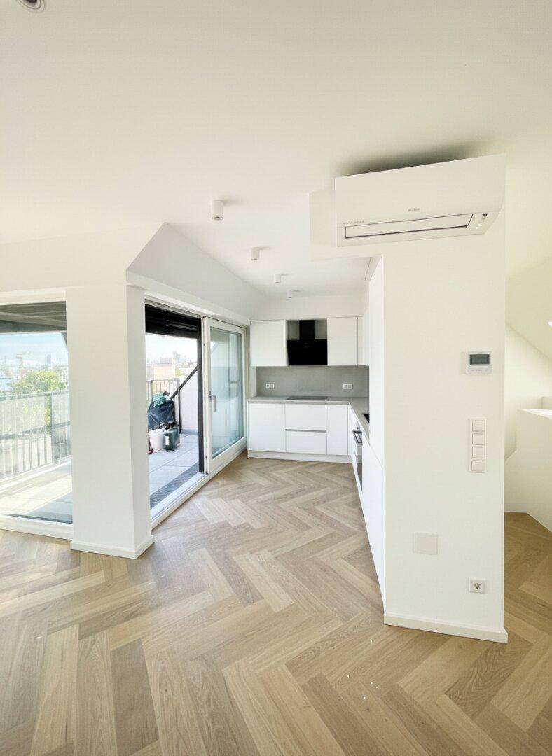 Moderne weiße Einbauküche im offenen Wohnbereich mit Zugang zur sonnigen Terrasse.