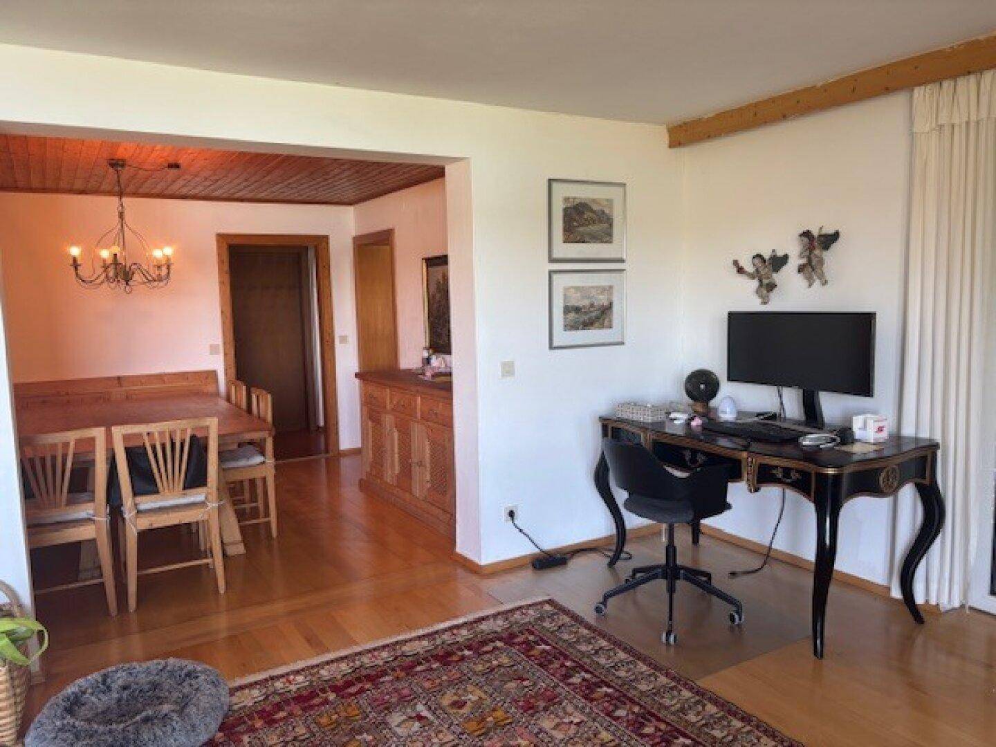 Offener Wohnbereich mit Essplatz, Schreibtisch und Holzboden unter einer Holzdecke.