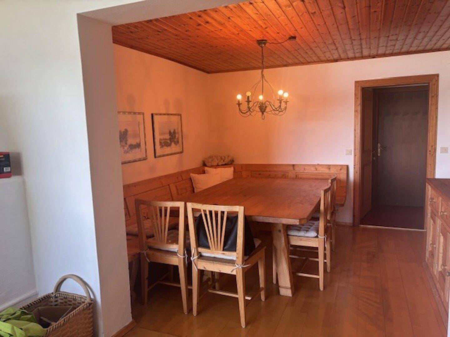 Traditioneller Essbereich mit Holztisch, Eckbank und passenden Stühlen unter einer Holzdecke.