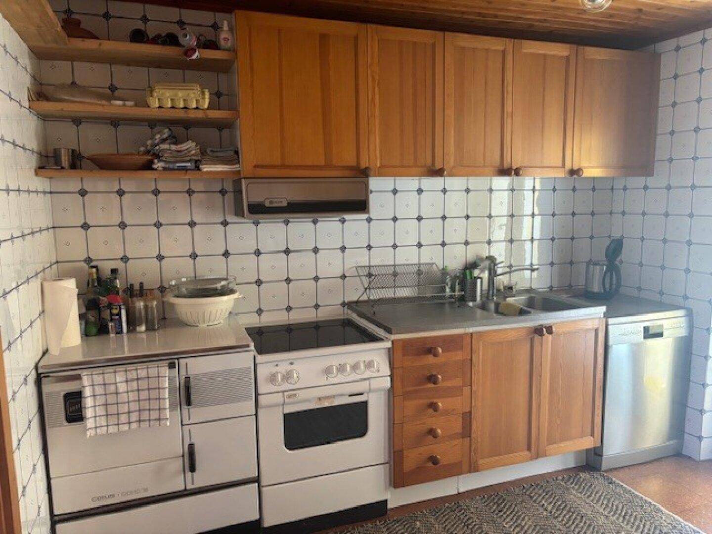 Kleine Küche im Landhausstil mit Holzschränken, Fliesenrückwand und integrierten Geräten.