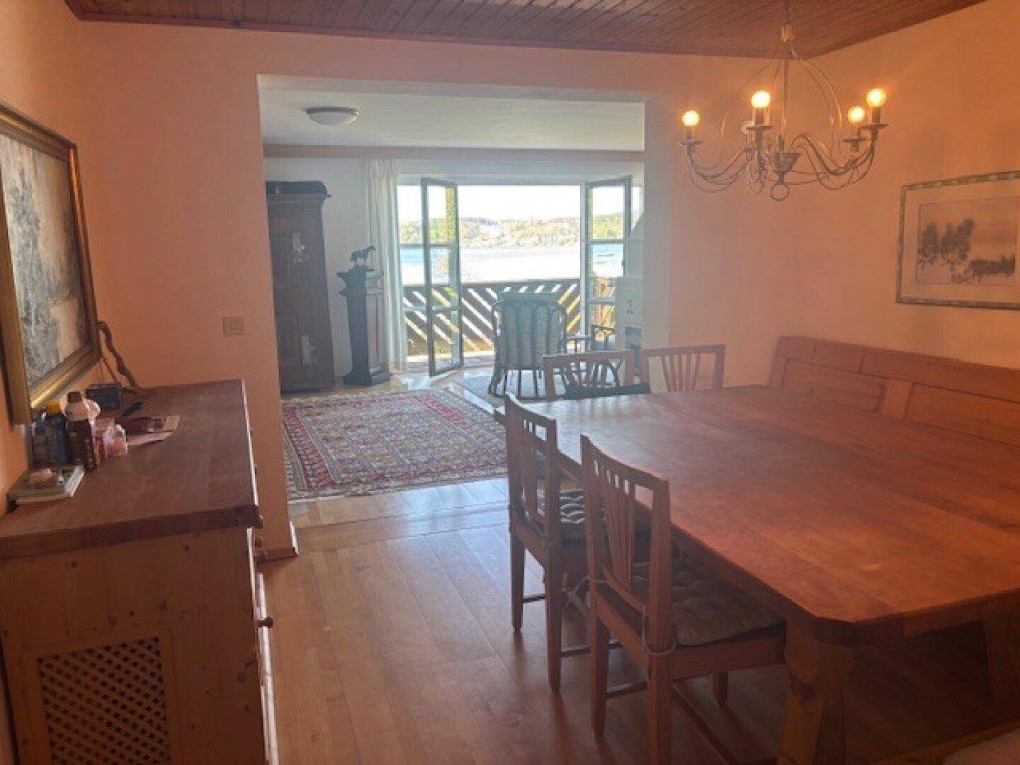 Gemütlicher Essbereich mit Holztisch und Zugang zu einem Balkon mit Seeblick.