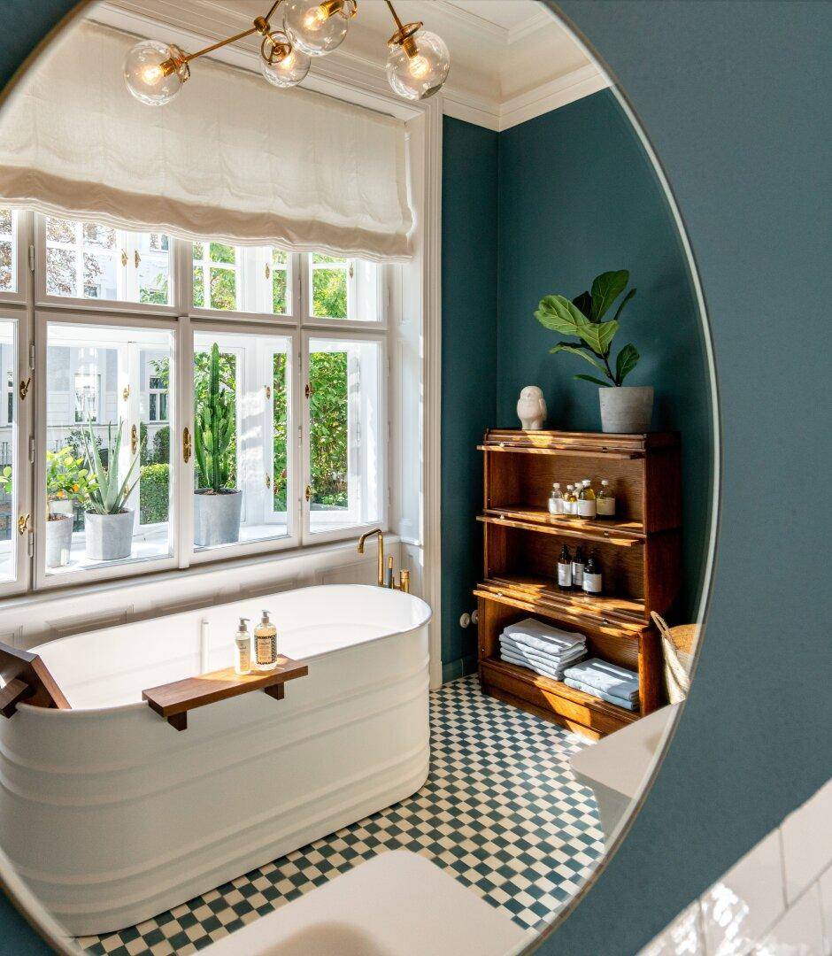 Modernes Badezimmer mit freistehender Badewanne, gemusterten Fliesen und großen Fenstern.