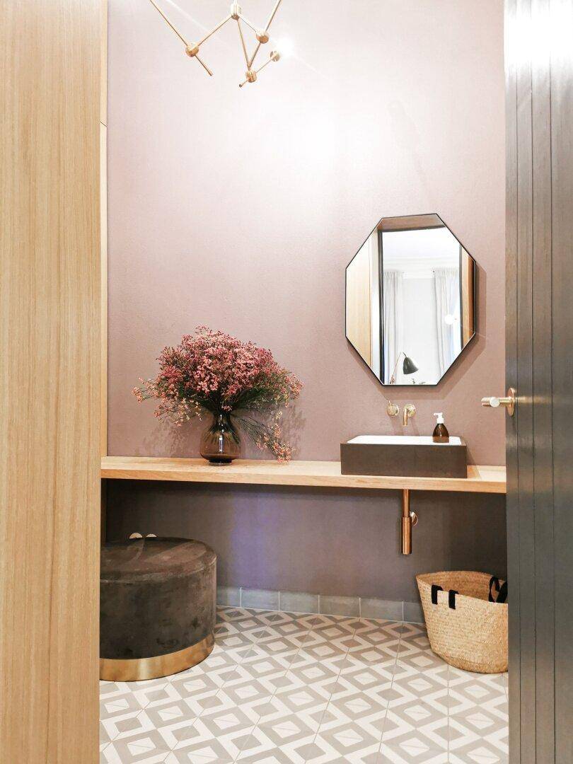 Modernes Gäste-WC mit rosa Wänden, stilvollem Waschbecken und gemusterten Fliesen.