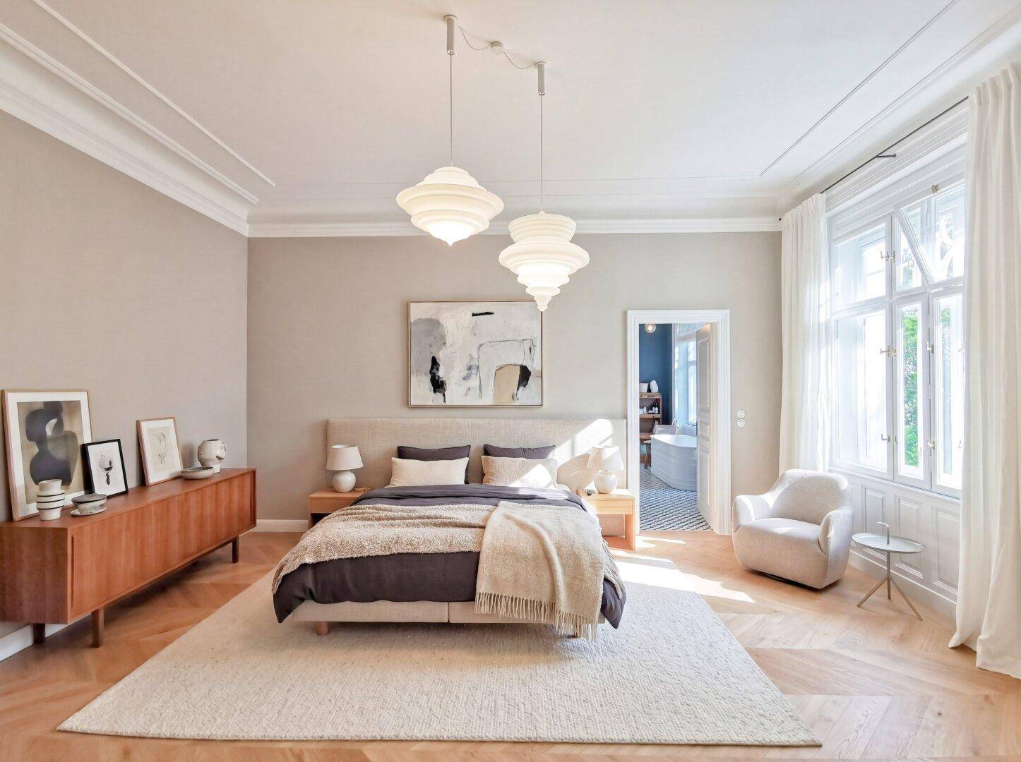 Geräumiges Schlafzimmer mit Doppelbett, Holzboden und großen Fenstern, die viel Licht hereinlassen.