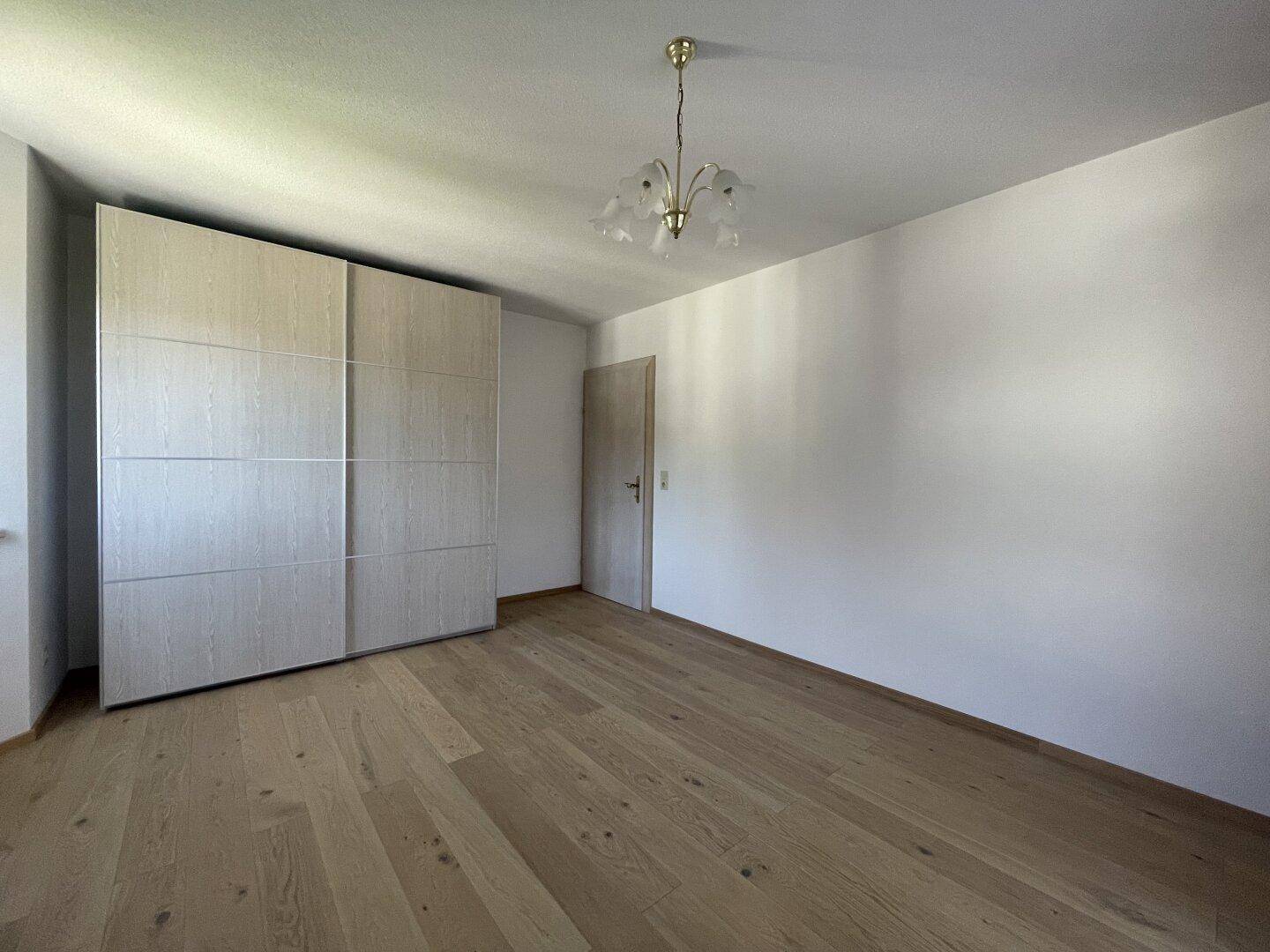 Helles Schlafzimmer mit Holzboden und großem Einbauschrank, bietet viel Stauraum.