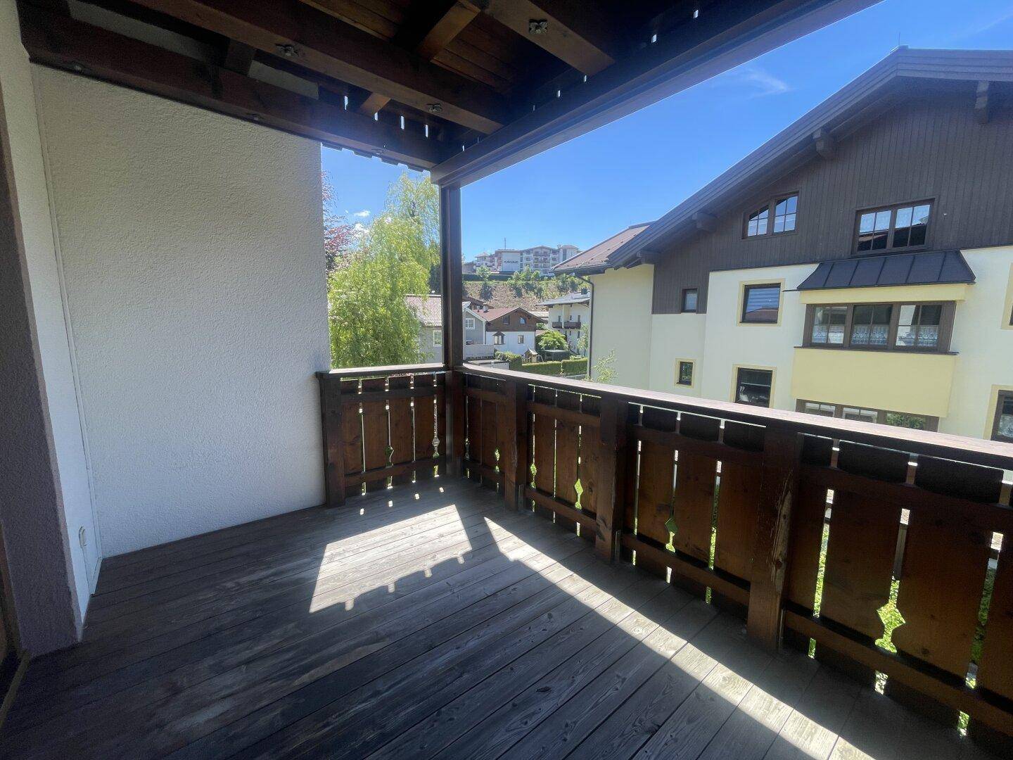 Überdachter Holzbalkon mit traditionellem Geländer und Blick auf die umliegenden Gebäude.