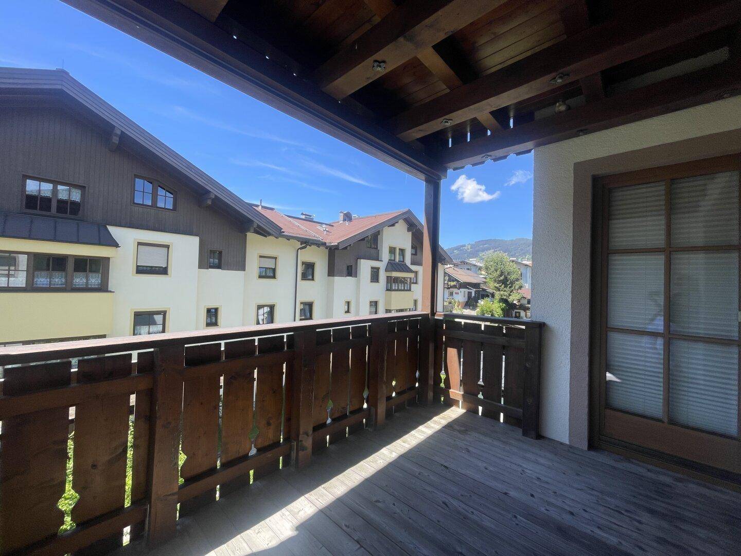 Geräumiger Holzbalkon mit Blick auf die Nachbarschaft und die dahinterliegenden Berge.