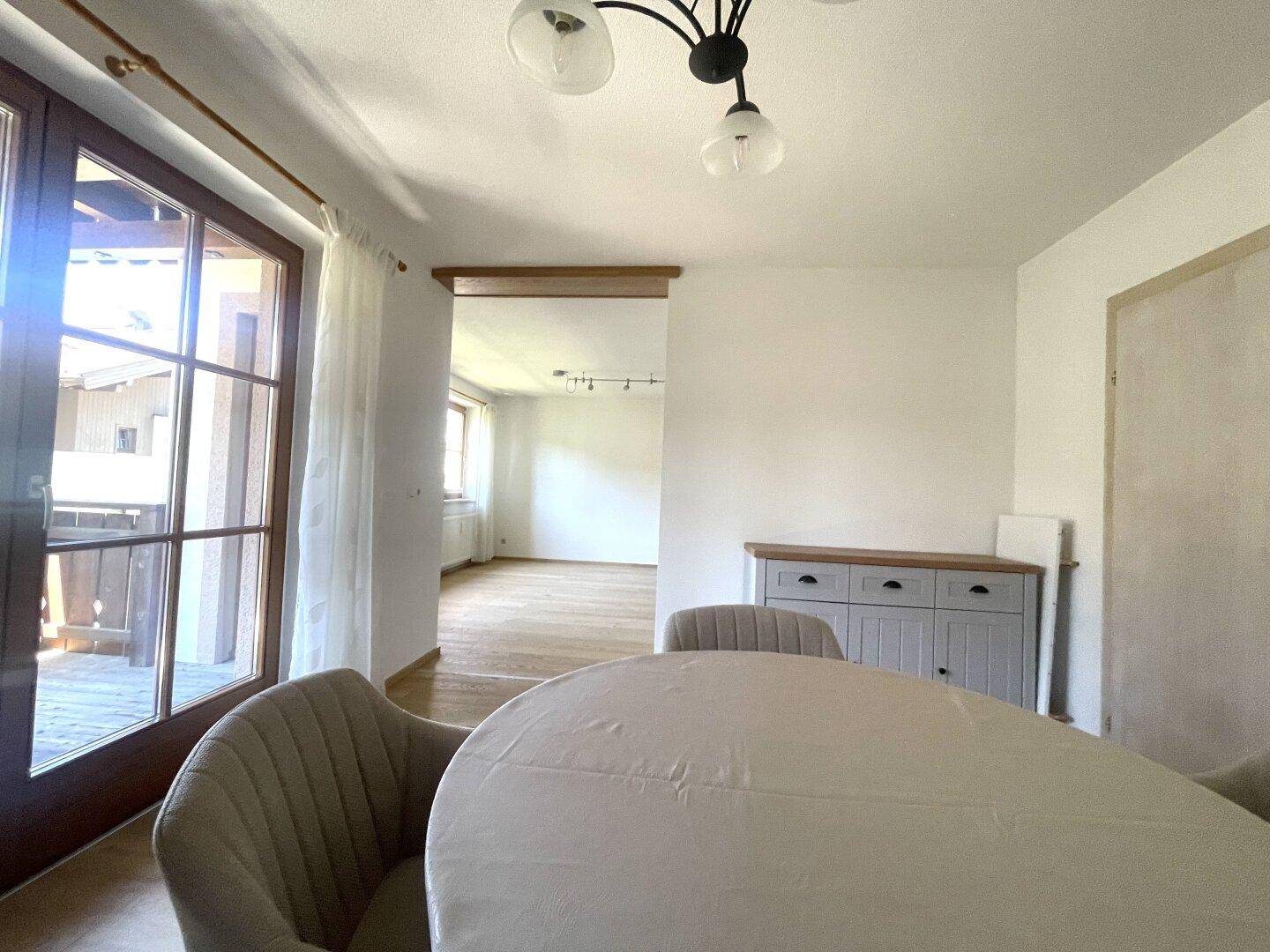 Essbereich mit Holzboden und Blick in das angrenzende Wohnzimmer, mit einem Sideboard.