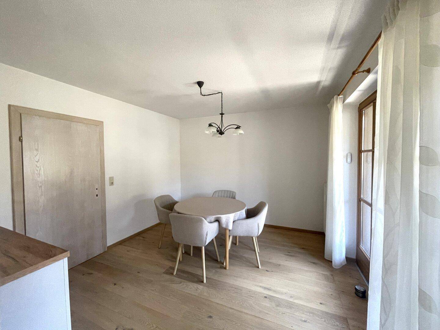 Heller Essbereich mit Holzboden und Zugang zu einem Balkon, ausgestattet mit einem runden Tisch.