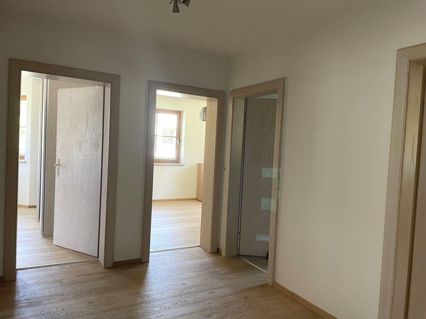 Flur mit Holzboden und mehreren Türen, die zu den angrenzenden Wohnräumen führen.