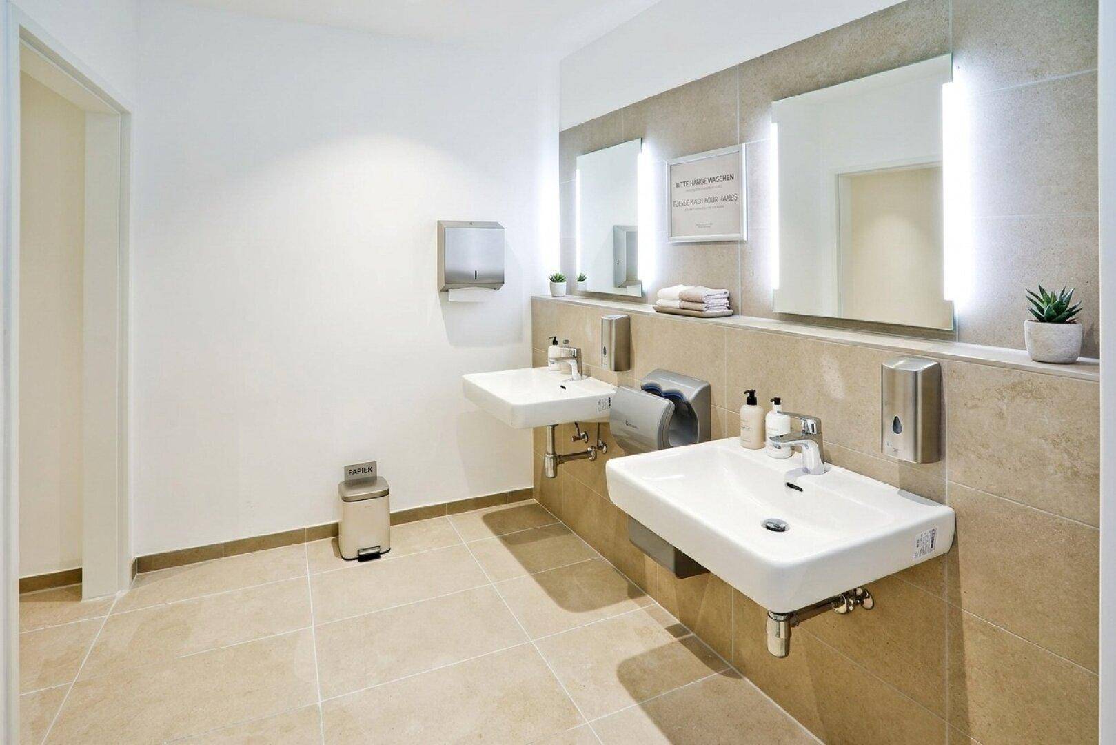 Heller und sauberer Sanitärbereich mit zwei Waschbecken, großen Spiegeln und modernen Armaturen.