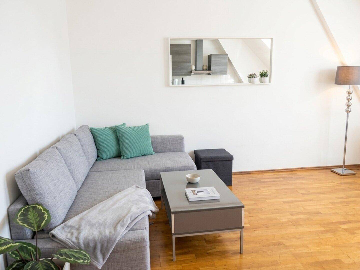 Gemütliches Wohnzimmer mit Ecksofa, Holzboden und moderner Dekoration.