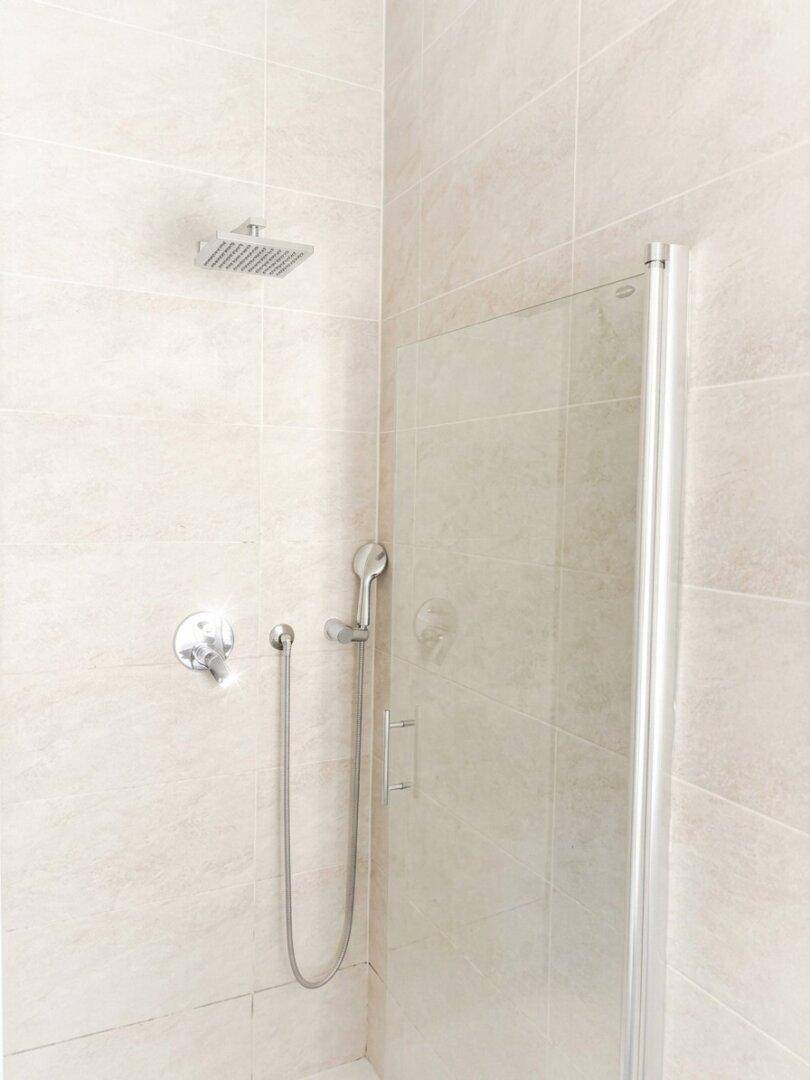 Duschbereich im Badezimmer mit Regendusche und Glasabtrennung.
