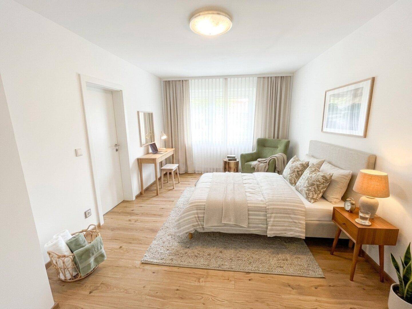 Gemütliches Schlafzimmer mit Holzboden, Doppelbett und Schreibtisch am Fenster.