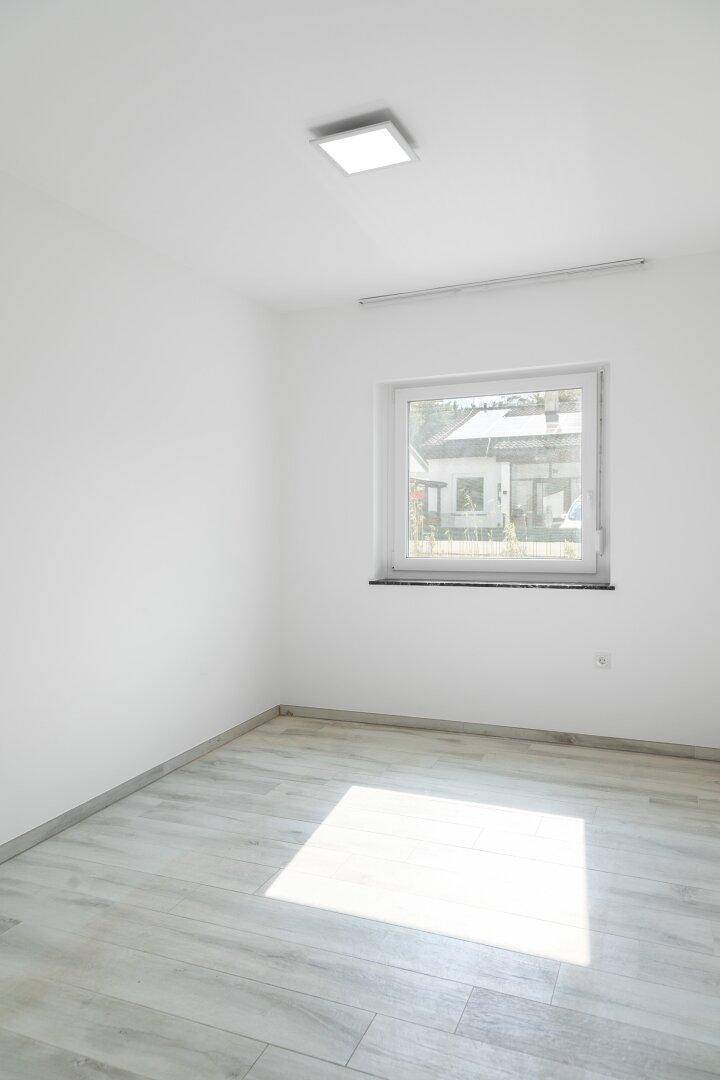 Helles Zimmer mit Laminatboden, großem Fenster und viel natürlichem Licht.