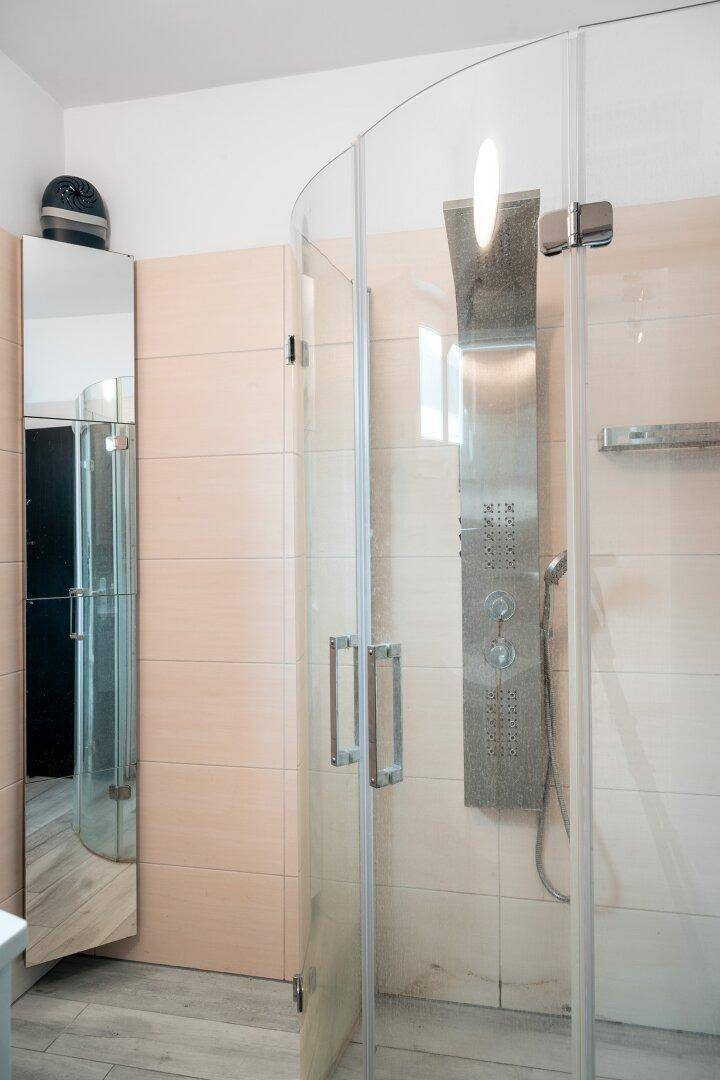 Modernes Badezimmer mit eleganter Glasdusche und hellen, großformatigen Fliesen.