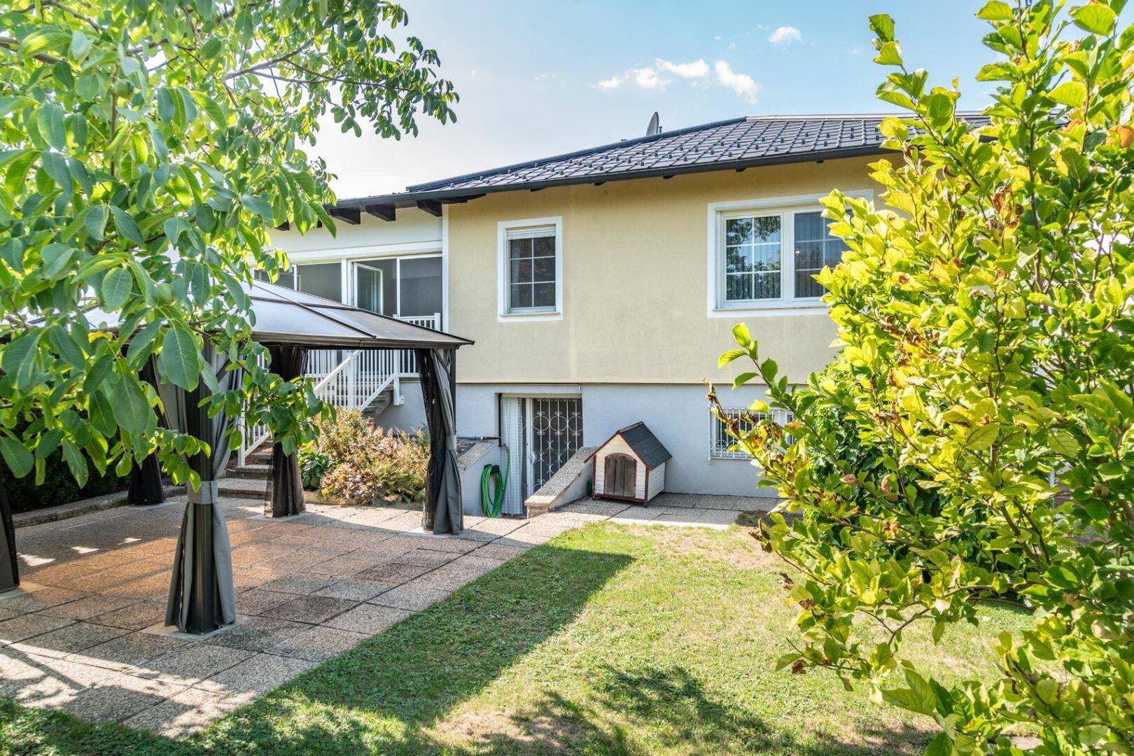 Gepflegter Garten mit Rasenfläche, Terrasse und Pavillon im Grünen.