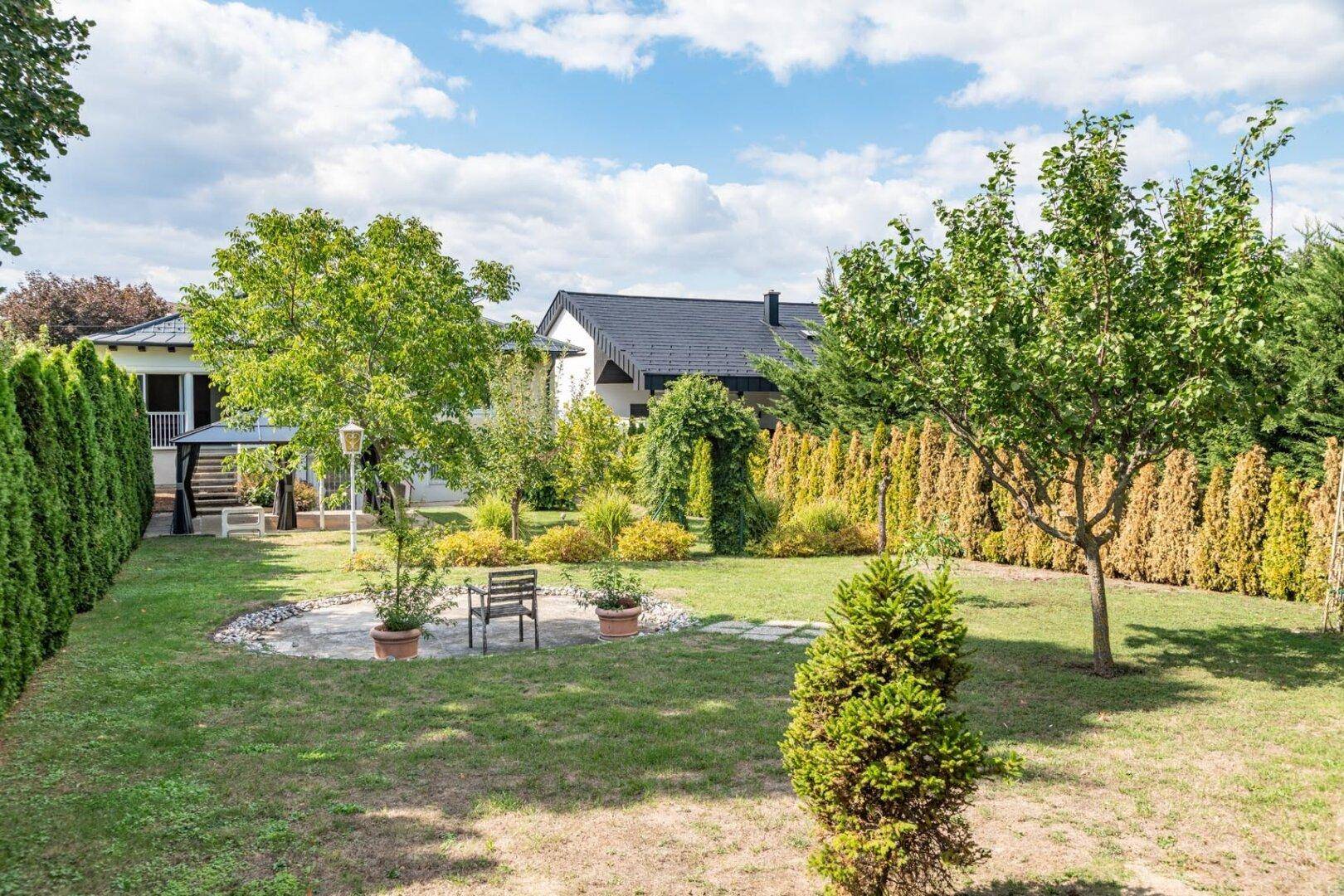 Weitläufiger Garten mit Rasen, Hecken und verschiedenen Pflanzen.