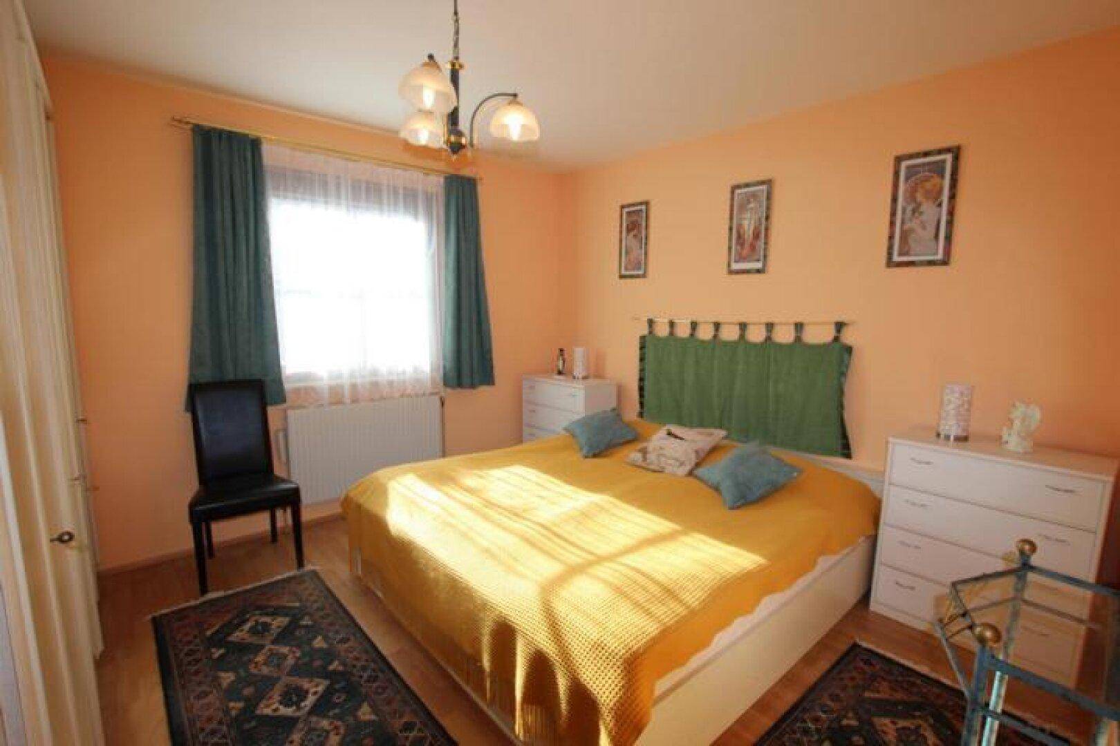 Schlafzimmer mit Doppelbett, Holzboden und Fenster mit Blick ins Grüne.