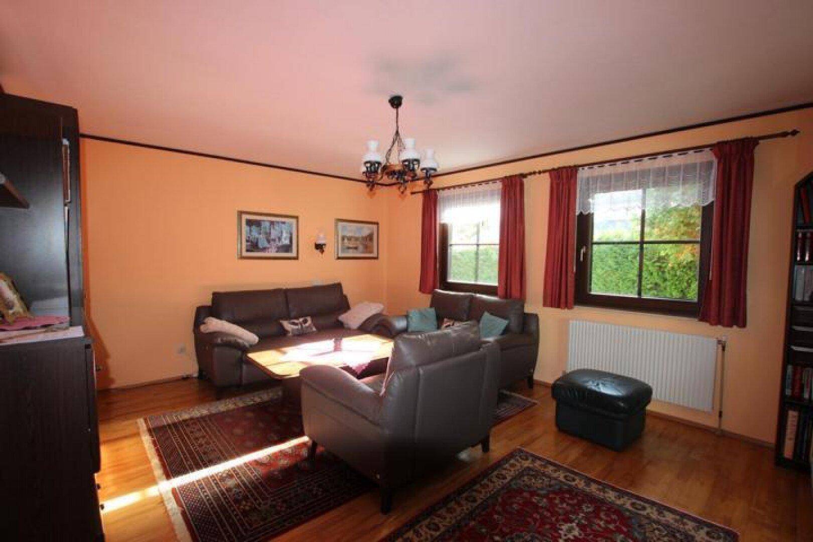 Helles Wohnzimmer mit Holzboden, bequemen Sofas und Blick in den grünen Garten.