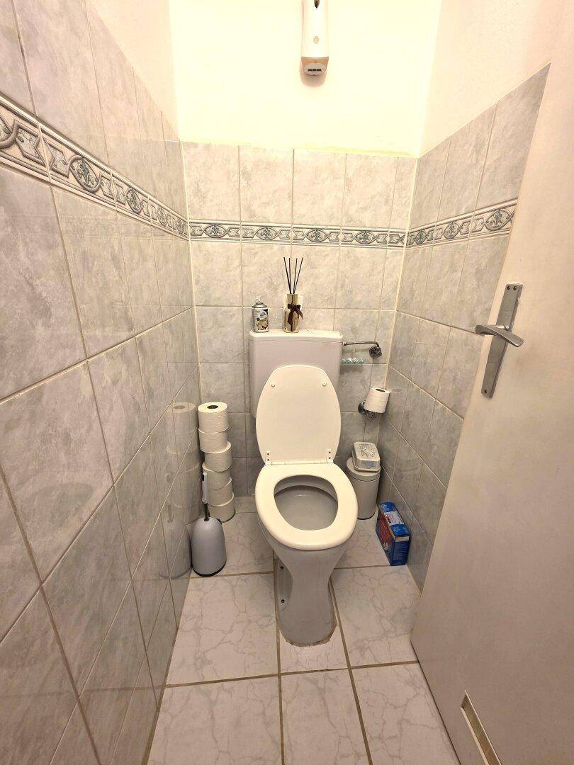 Separate Toilette mit hellen Fliesen und einfacher Ausstattung.
