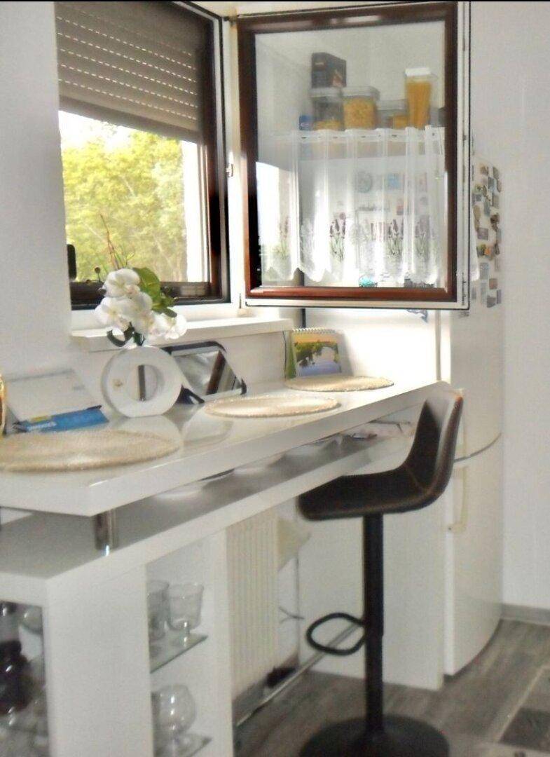 Küchenzeile mit Frühstücksbar, Barhocker und Fenster mit Blick ins Grüne.