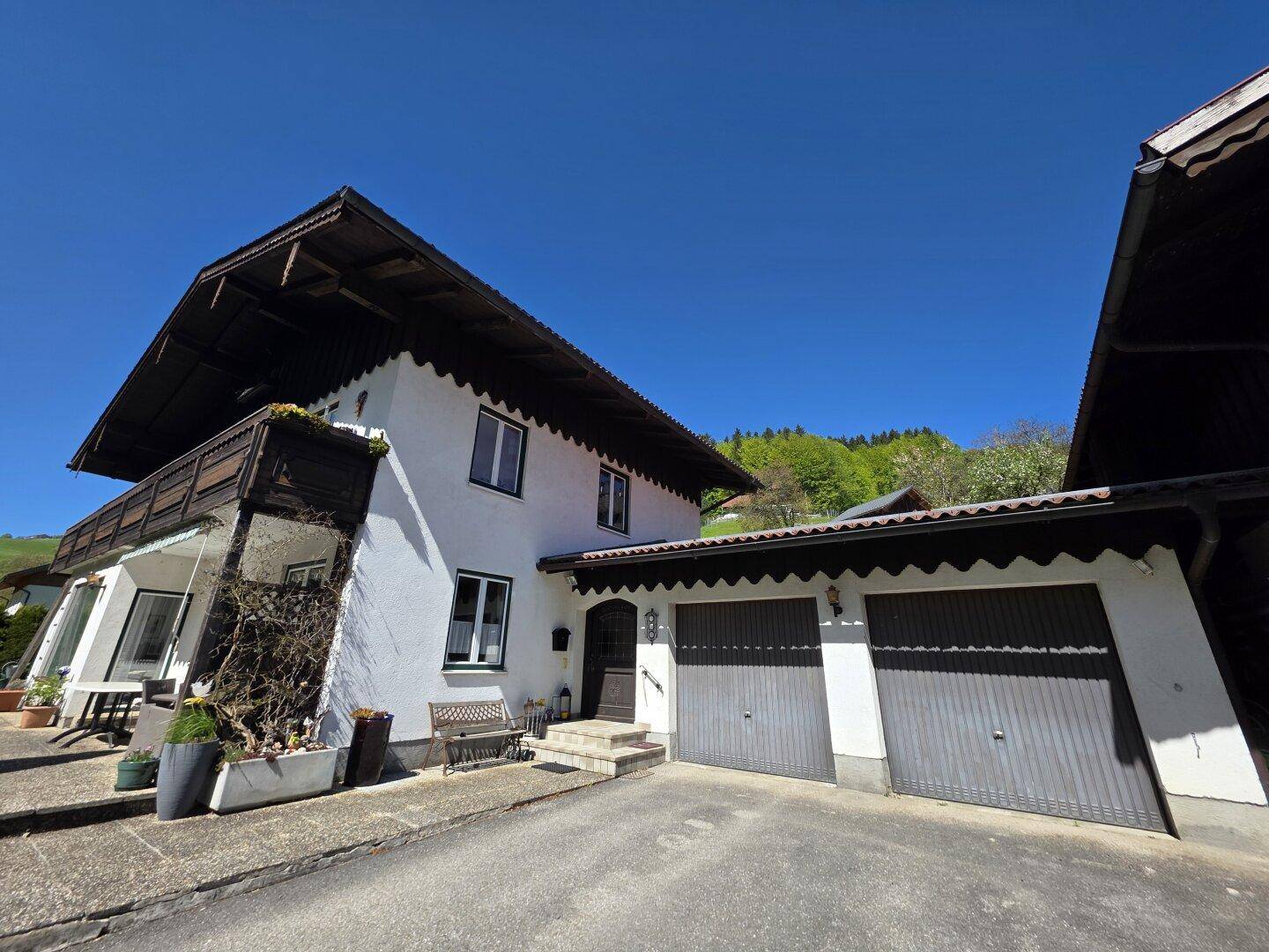 Haupthaus mit traditioneller Fassade und integrierter Doppelgarage unter strahlend blauem Himmel.