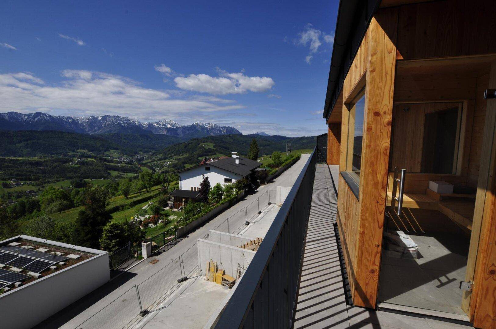 Langer Balkon entlang des Gebäudes mit Holzfassade und Bergblick.