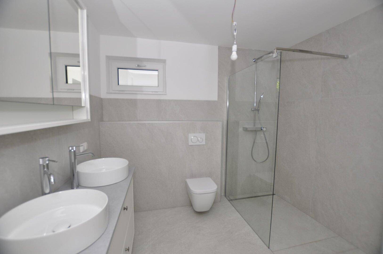Modernes Badezimmer mit Doppelwaschbecken, begehbarer Dusche und Fenster.