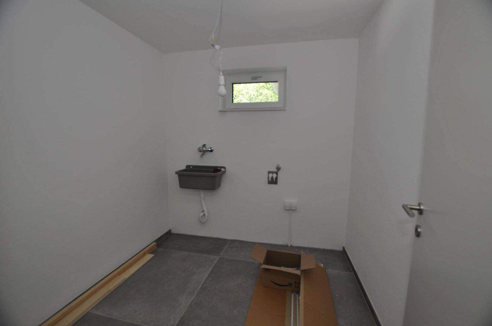 Hauswirtschaftsraum mit Waschbecken und Fenster, bereit für Installationen.