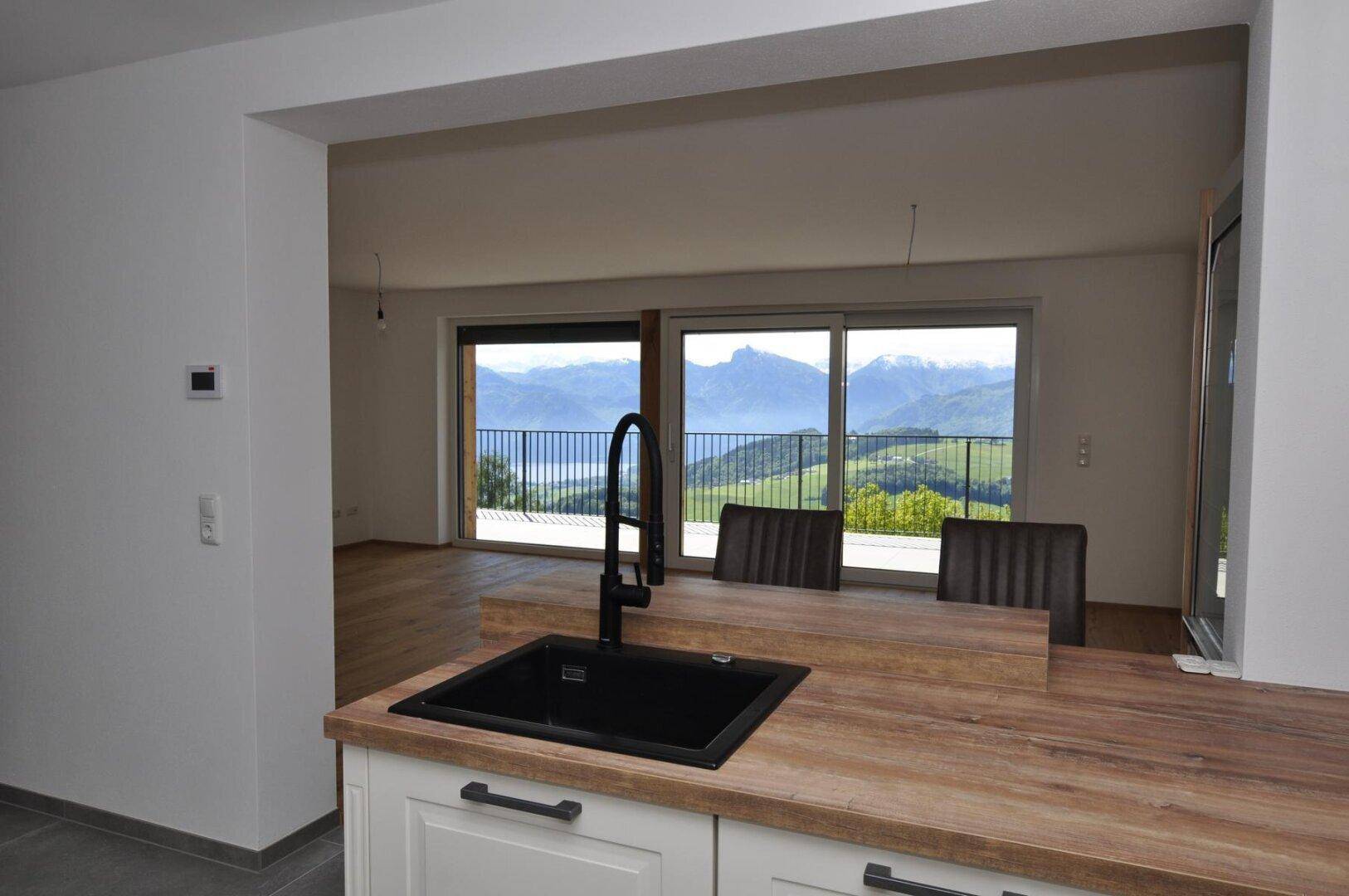 Offene Küche mit Frühstücksbar und Blick vom Spülbecken auf die Berge und den See.
