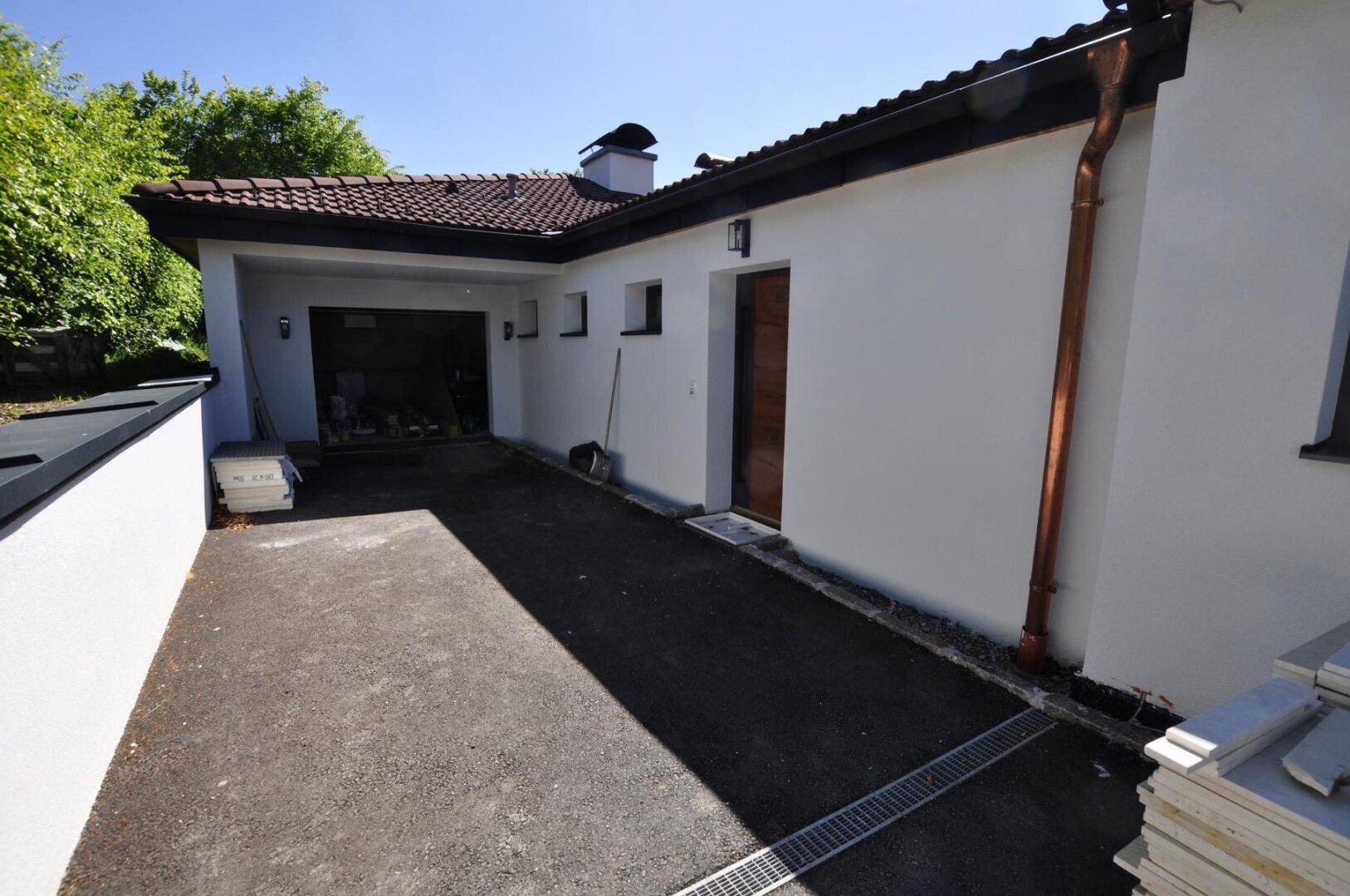 Einfahrt und Garagenbereich eines Neubaus mit weißer Fassade.