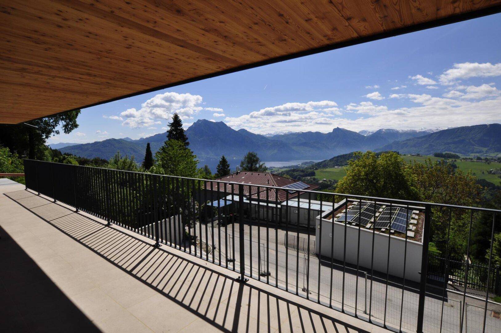 Breiter Balkon mit Holzdach und weitem Panoramablick über die Landschaft und Berge.
