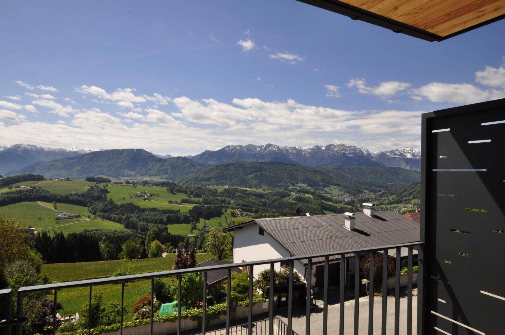 Balkon mit Blick auf die grüne Hügellandschaft und die majestätischen Berge im Hintergrund.