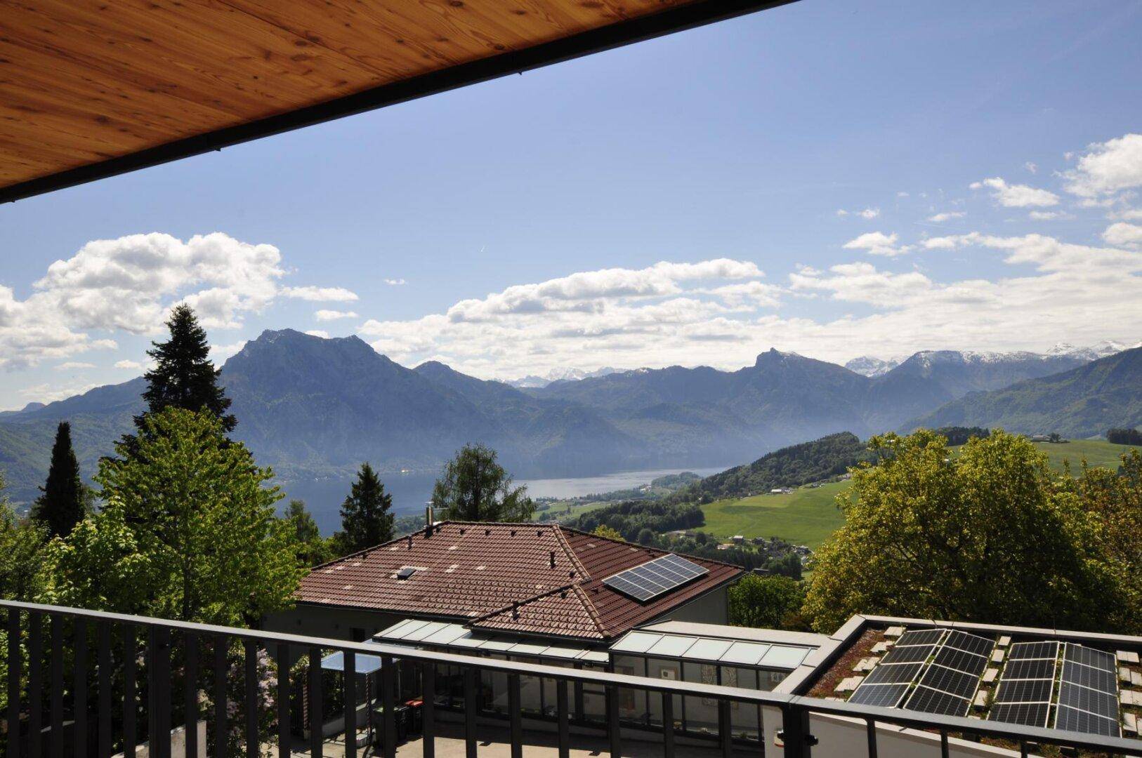 Balkon mit weitem Blick auf die Berge, den See und die umliegende grüne Landschaft.