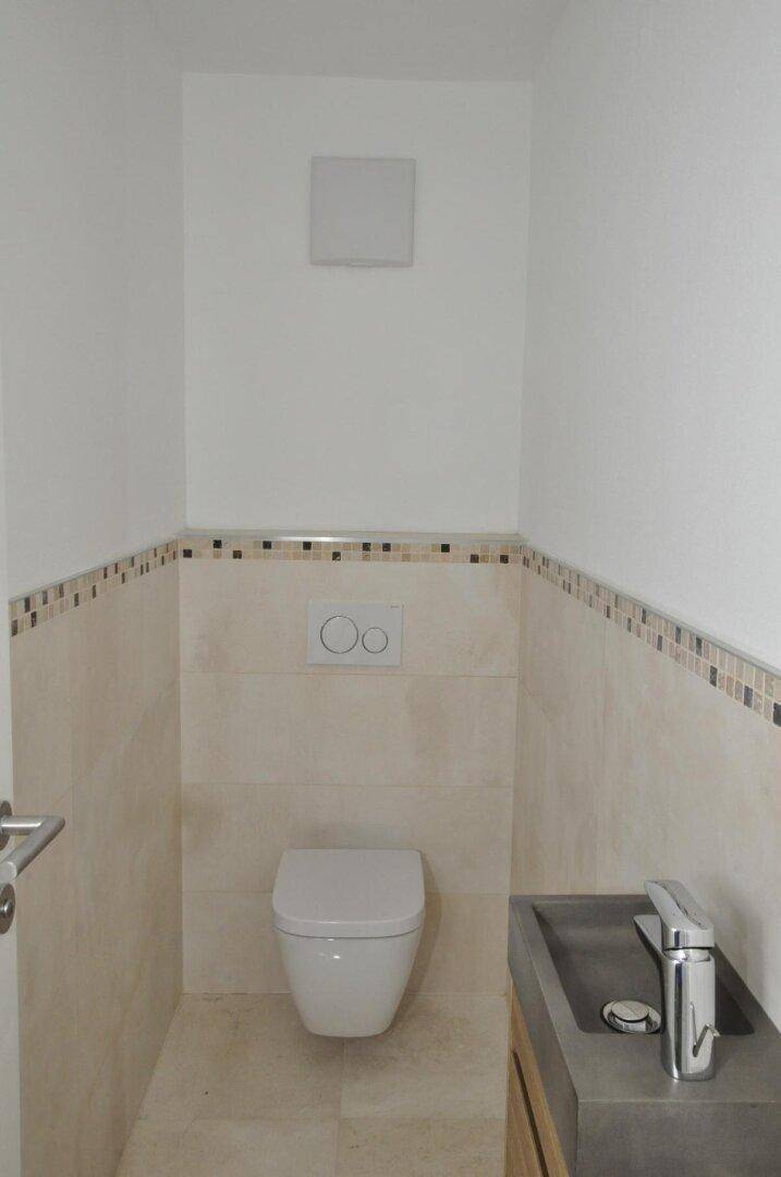 Kleines Gäste-WC mit wandhängendem WC und modernem Waschbecken in neutralen Farben.