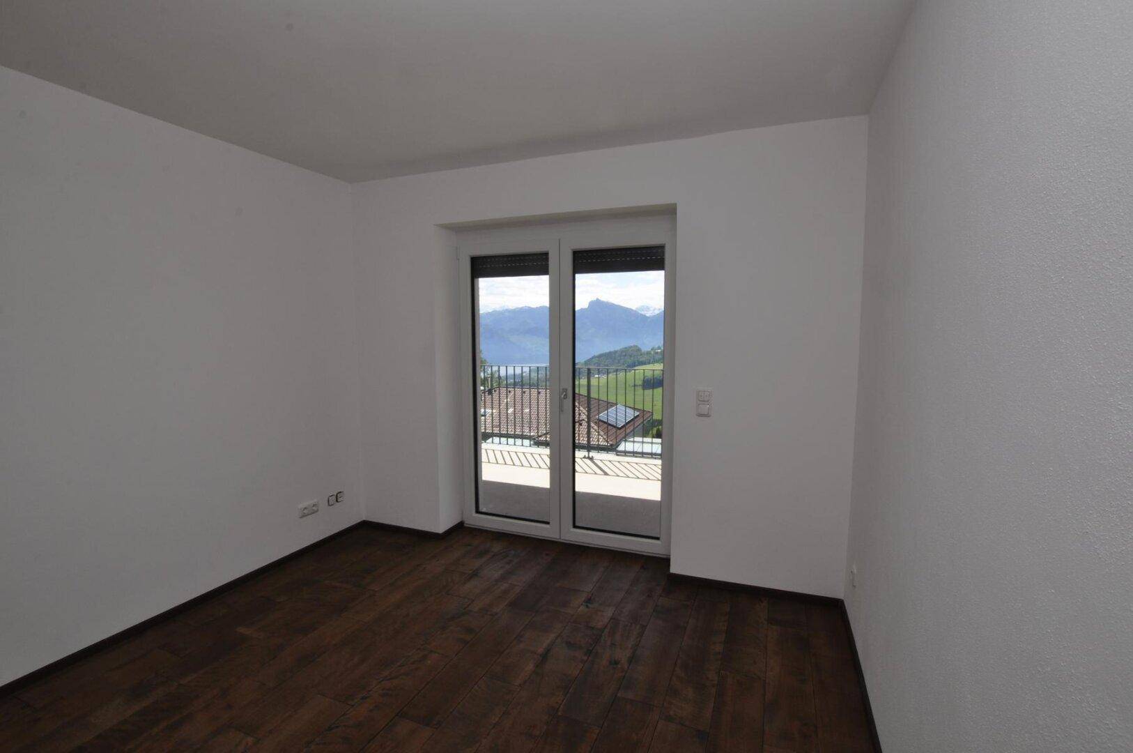 Schlafzimmer mit Holzboden und Balkonzugang, bietet einen weiten Blick auf die Landschaft.