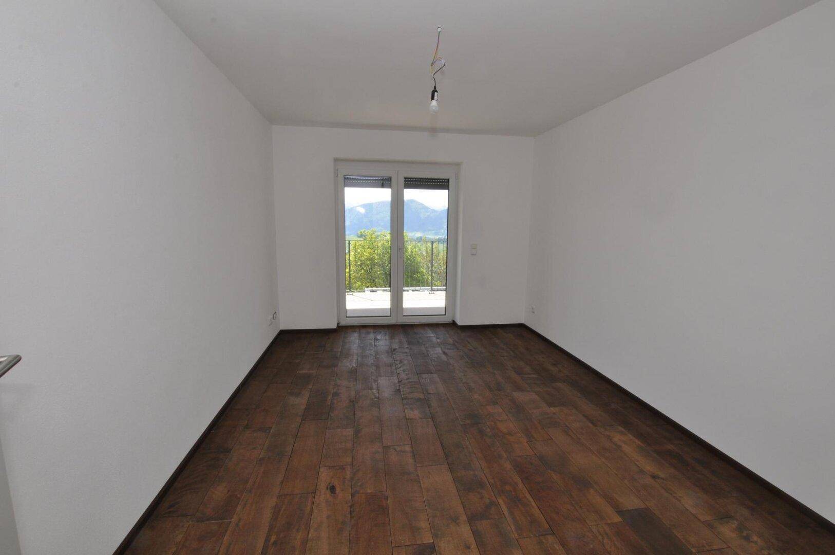 Geräumiges Schlafzimmer mit Holzboden und großen Fenstern mit Blick auf die Berge.