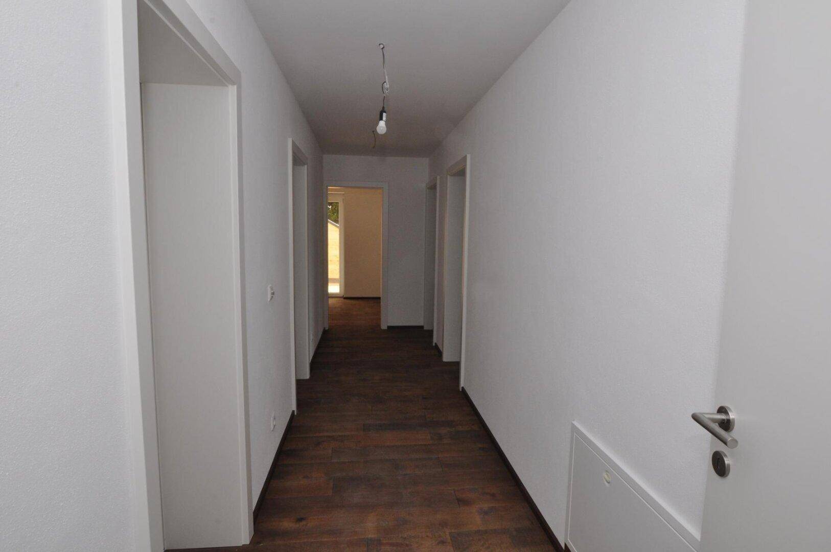 Heller Flur mit Holzboden und weißen Wänden, der eine offene Atmosphäre schafft.